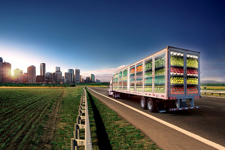 A truck on a highway going into the city. Truck is transparent and you can see the produce it is carrying.